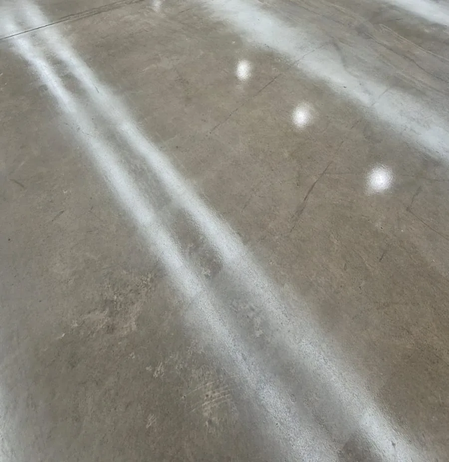 Piso de concreto polido cinza contínuo com reflexo suave de luz
