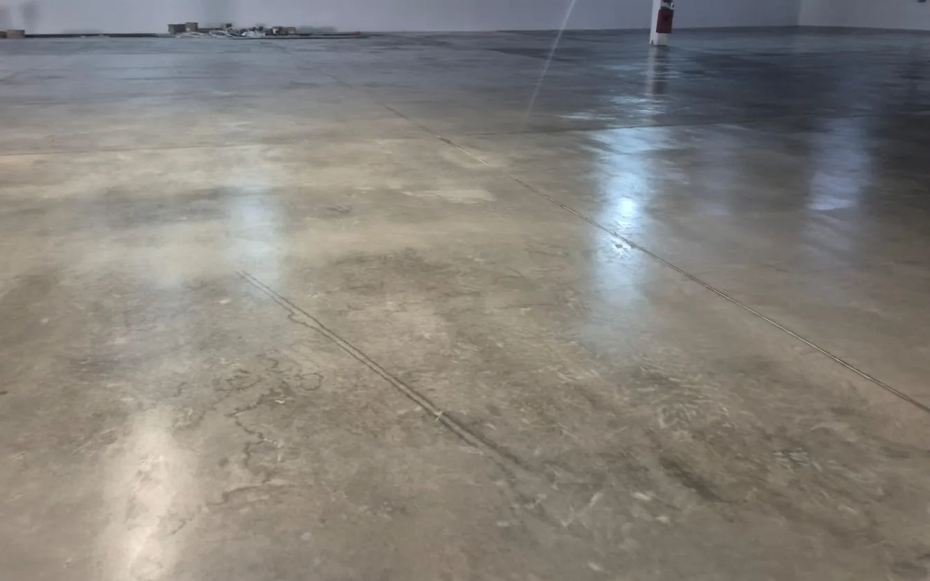 Galpão industrial amplo com piso de concreto polido, reflexos das luminárias no chão