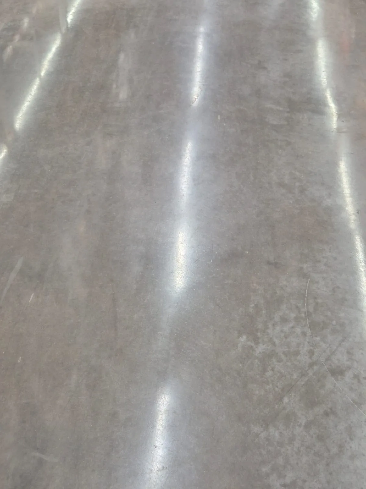 Close de piso de concreto polido com reflexo intenso de luminária