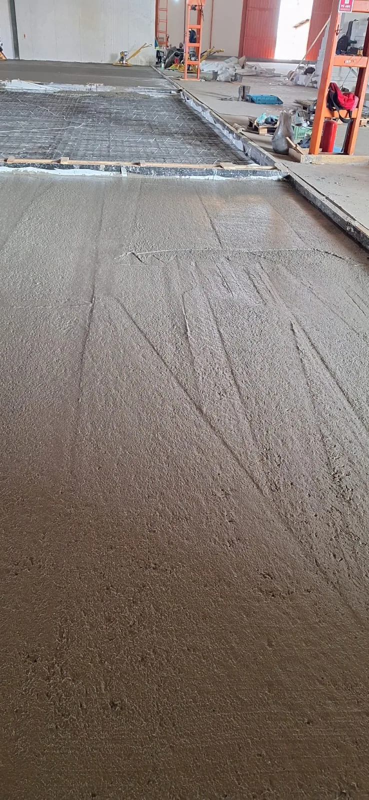 Concreto recém-lançado sendo nivelado sobre a malha de aço