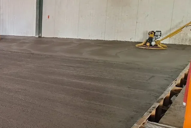 Acabadora mecânica alisando o concreto ainda fresco no galpão